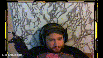 A Man With A Beard Is Wearing Headphones And Holding A Microphone While Sitting On A Bed GIF