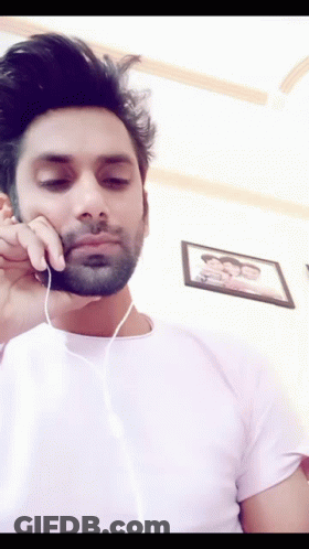 A Man With A Beard Is Wearing Headphones And Looking Down GIF