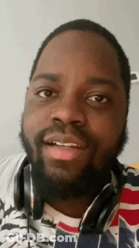 A Man With A Beard Is Wearing Headphones And Making A Face . GIF