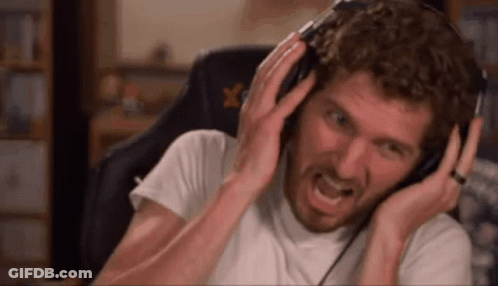 A Man With A Beard Is Wearing Headphones And Making A Funny Face . GIF