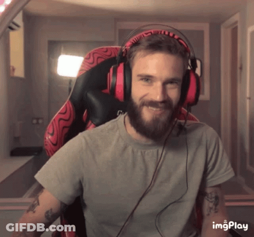 A Man With A Beard Is Wearing Headphones And Smiling While Sitting In An Office Chair GIF