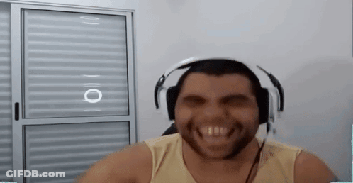 A Man With A Beard Is Wearing Headphones And Smiling While Sitting In Front Of A Window . GIF