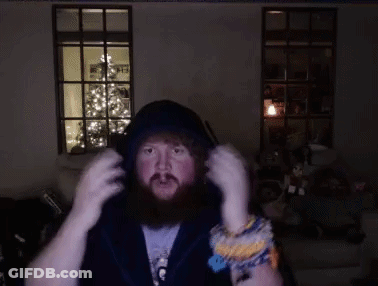 A Man With A Beard Is Wearing Headphones In A Dark Room With A Christmas Tree In The Background GIF