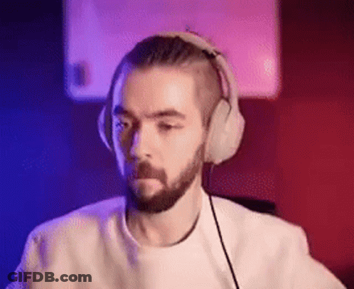 A Man With A Beard Is Wearing Headphones While Sitting In Front Of A Computer . GIF