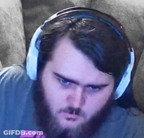 A Man With A Beard Is Wearing Headphones While Sitting On A Couch . GIF