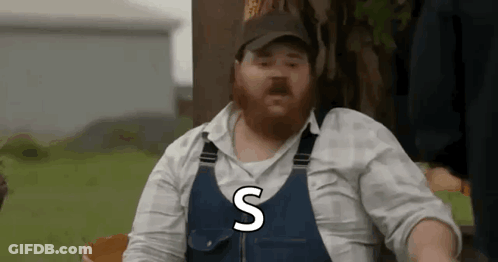 A Man With A Beard Is Wearing Overalls And A Hat And Says The Letter S . GIF