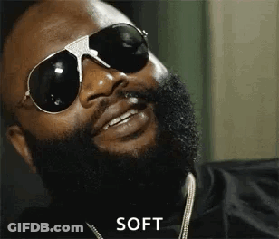 A Man With A Beard Is Wearing Sunglasses And A Necklace . GIF
