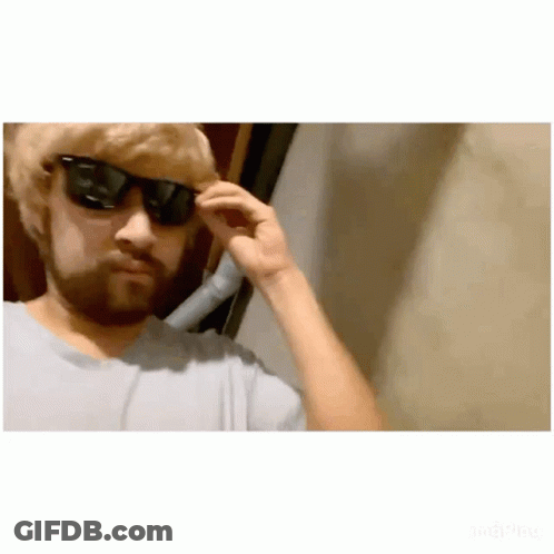 A Man With A Beard Is Wearing Sunglasses And Adjusting His Glasses . GIF