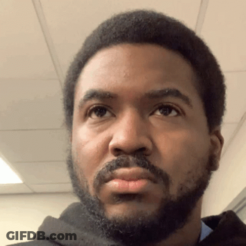 A Man With A Beard Looks At The Camera GIF