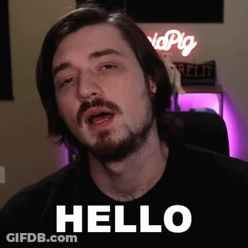 A Man With A Beard Says Hello In Front Of A Pink Sign GIF