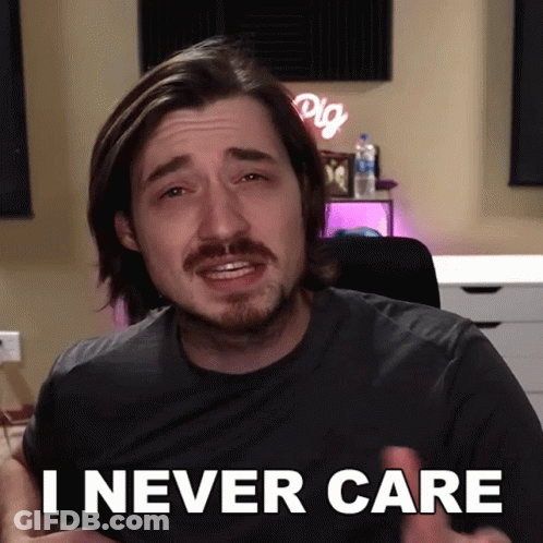A Man With A Beard Says " I Never Care " In Front Of A Desk GIF