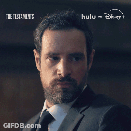 A Man With A Beard Says " Not Yet " In Front Of A Poster For The Testaments GIF