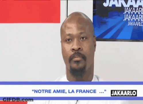 A Man With A Beard Says " Notre Amie La France " On A Screen GIF