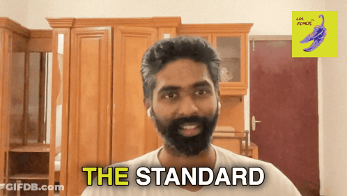 A Man With A Beard Says " The Standard " In A Room GIF