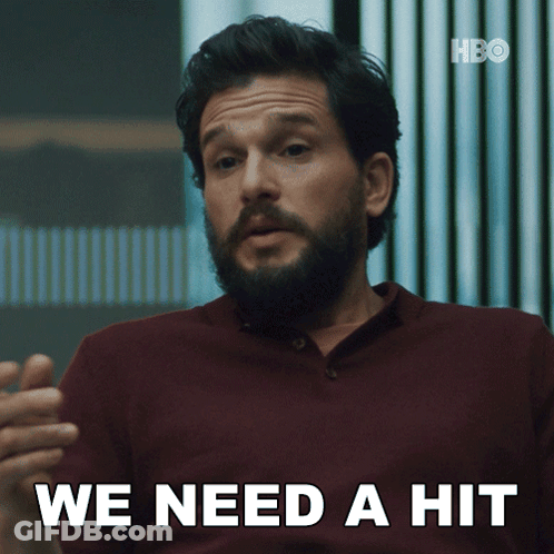 A Man With A Beard Says " We Need A Hit " In White Letters GIF