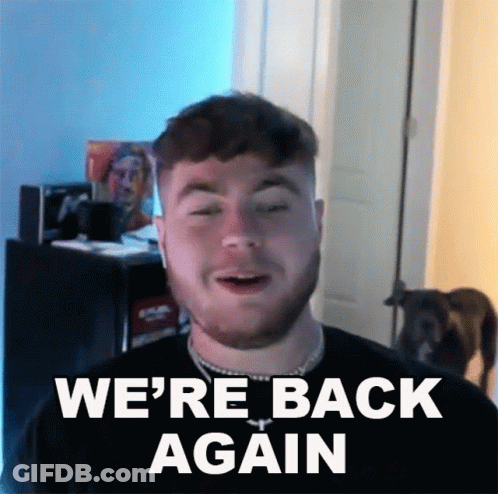 A Man With A Beard Says " We 'Re Back Again " In Front Of A Dog GIF