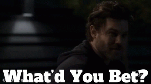 A Man With A Beard Says " What 'D You Bet " In A Dark Room GIF