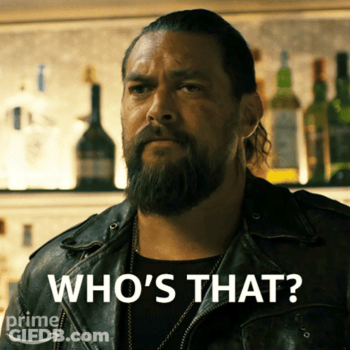 A Man With A Beard Says Who 'S That In Front Of A Bar GIF
