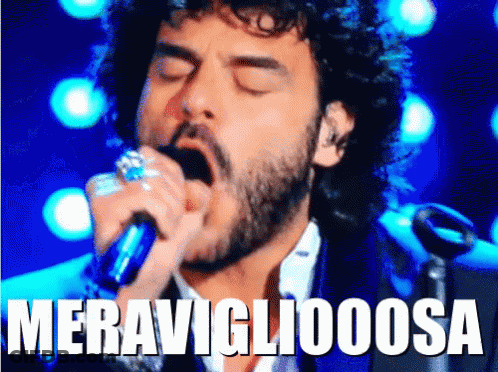 A Man With A Beard Singing Into A Microphone With The Word Meravigliaoosa Written Above Him GIF