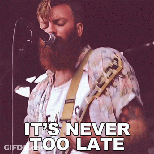 A Man With A Beard Singing Into A Microphone With The Words It 'S Never Too Late Below Him GIF
