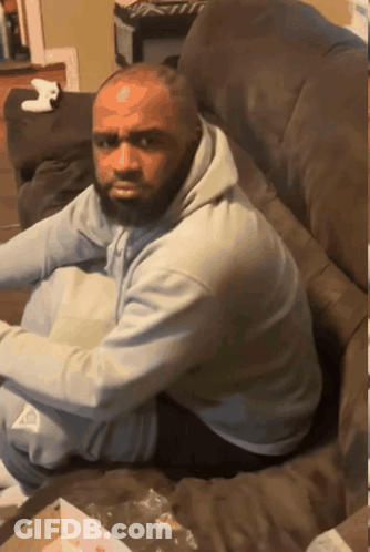 A Man With A Beard Sits On A Couch GIF