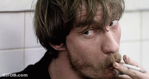 A Man With A Beard Smoking A Cigarette In A Bathroom GIF