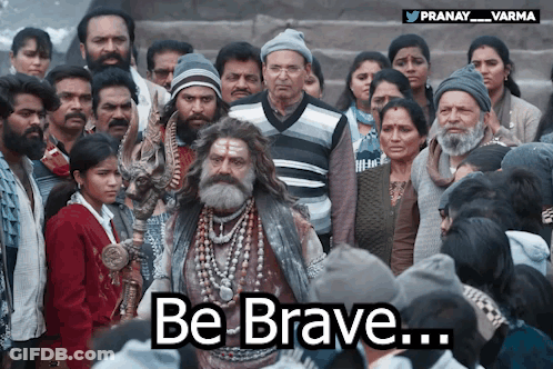 A Man With A Beard Stands In Front Of A Crowd With The Words Be Brave Written Below Him GIF