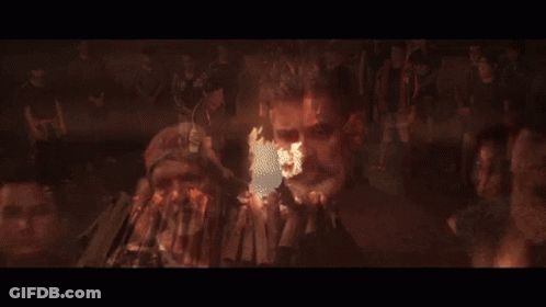 A Man With A Beard Stands In Front Of A Large Fire GIF