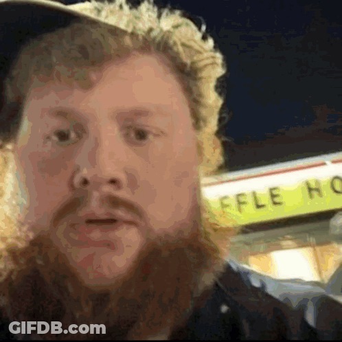 A Man With A Beard Stands In Front Of A Waffle House Sign GIF
