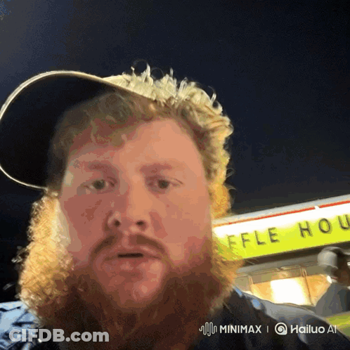 A Man With A Beard Stands In Front Of A Waffle House Sign GIF