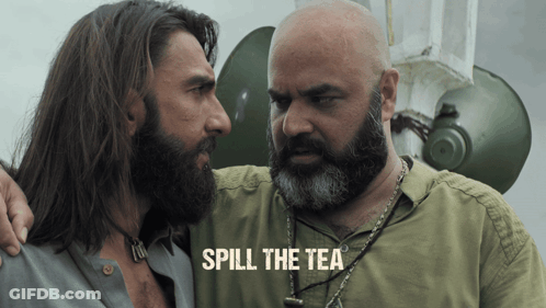 A Man With A Beard Stands Next To Another Man With The Words Spill The Tea On The Bottom GIF