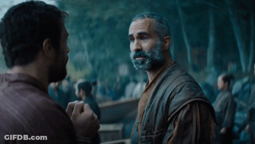 A Man With A Beard Talks To Another Man In Front Of A Crowd GIF