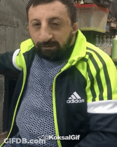 A Man With A Beard Wearing A Black And Yellow Adidas Jacket GIF
