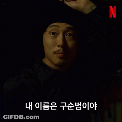 A Man With A Beard Wearing A Black Hat And A Black Jacket Is Talking In Korean . GIF