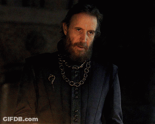A Man With A Beard Wearing A Black Jacket And A Gold Chain Around His Neck GIF