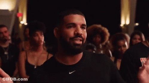 A Man With A Beard Wearing A Black Nike Shirt Is Standing In Front Of A Crowd . GIF