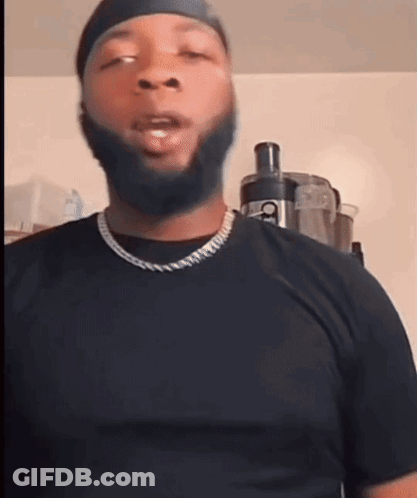 A Man With A Beard Wearing A Black Shirt And A Necklace GIF