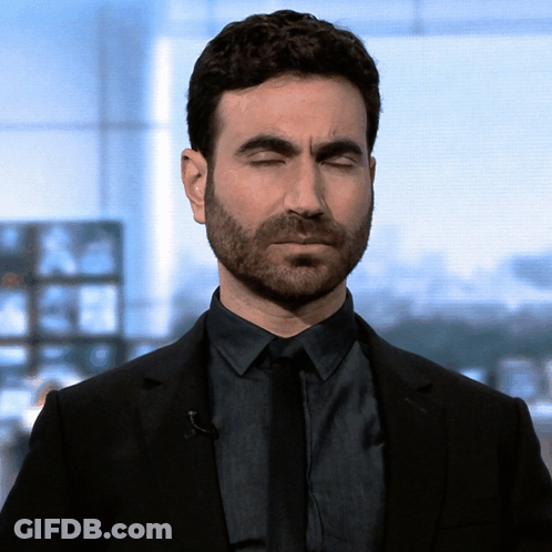 A Man With A Beard Wearing A Black Suit And Tie With His Eyes Closed GIF
