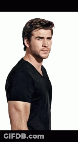 A Man With A Beard Wearing A Black T-Shirt Is Standing In Front Of A White Background GIF