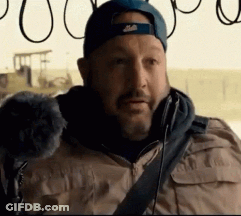 A Man With A Beard Wearing A Blue Hat And A Tan Jacket GIF