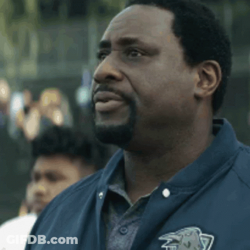 A Man With A Beard Wearing A Blue Jacket With A Lion On The Pocket GIF