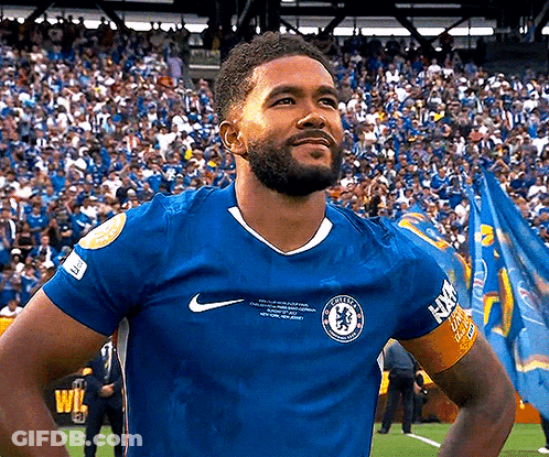 A Man With A Beard Wearing A Blue Nike Jersey Is Standing On A Soccer Field In Front Of A Crowd . GIF