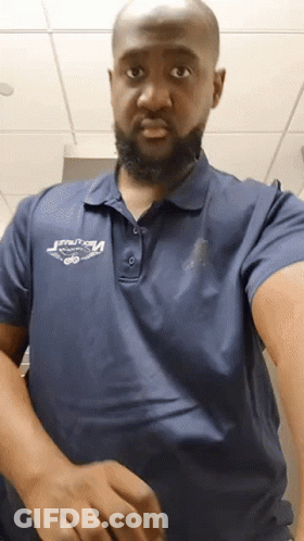 A Man With A Beard Wearing A Blue Polo Shirt That Says ' Velocity ' On It GIF