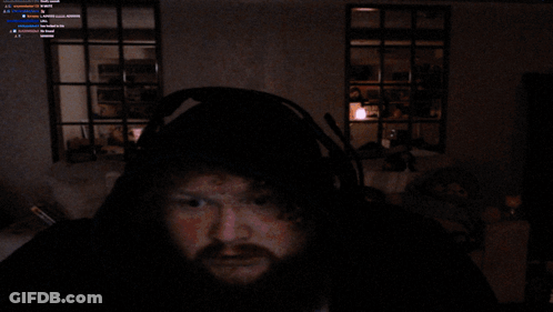 A Man With A Beard Wearing A Blue Robe And Headphones Looks At The Camera GIF