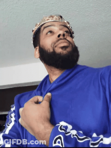 A Man With A Beard Wearing A Blue Shirt And A Crown On His Head GIF