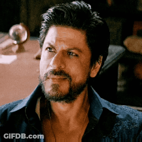 A Man With A Beard Wearing A Blue Shirt Is Looking At The Camera GIF