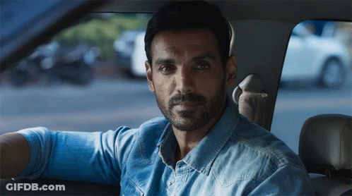 A Man With A Beard Wearing A Blue Shirt Is Sitting In A Car GIF