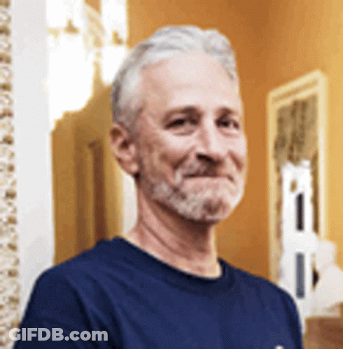 A Man With A Beard Wearing A Blue Shirt Is Smiling . GIF