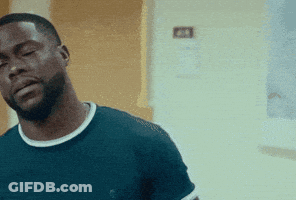 A Man With A Beard Wearing A Blue Shirt Is Standing In A Room With His Eyes Closed . GIF
