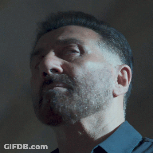 A Man With A Beard Wearing A Blue Shirt Looks At The Camera GIF